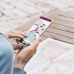 Young traveller woman sitting in a cafe terrace and planning trip with map and smartphone. Travel and active lifestyle concept